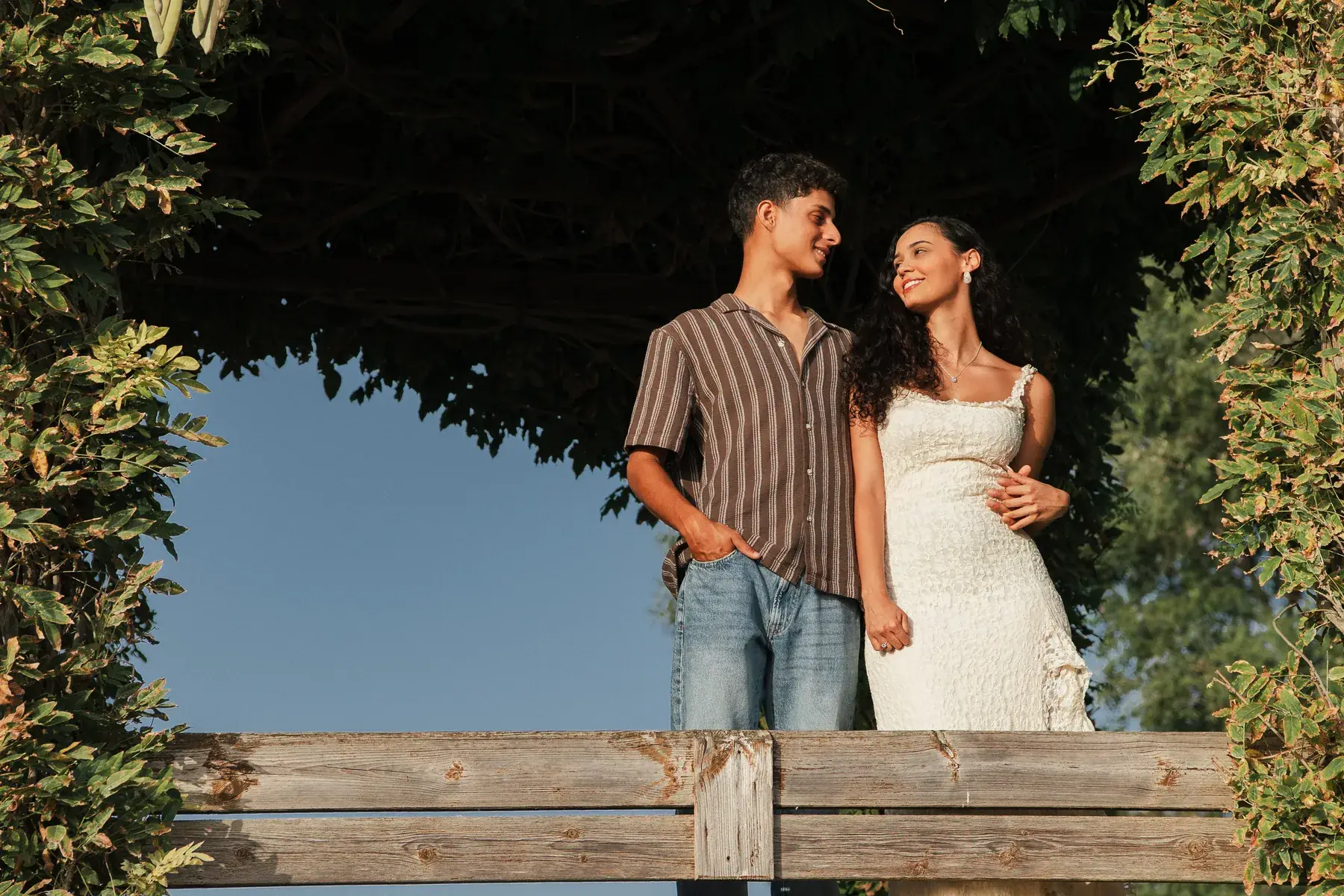 Noivos a olhar um para o outro sob uma pérgola de glicínias ao fim da tarde no Algarve